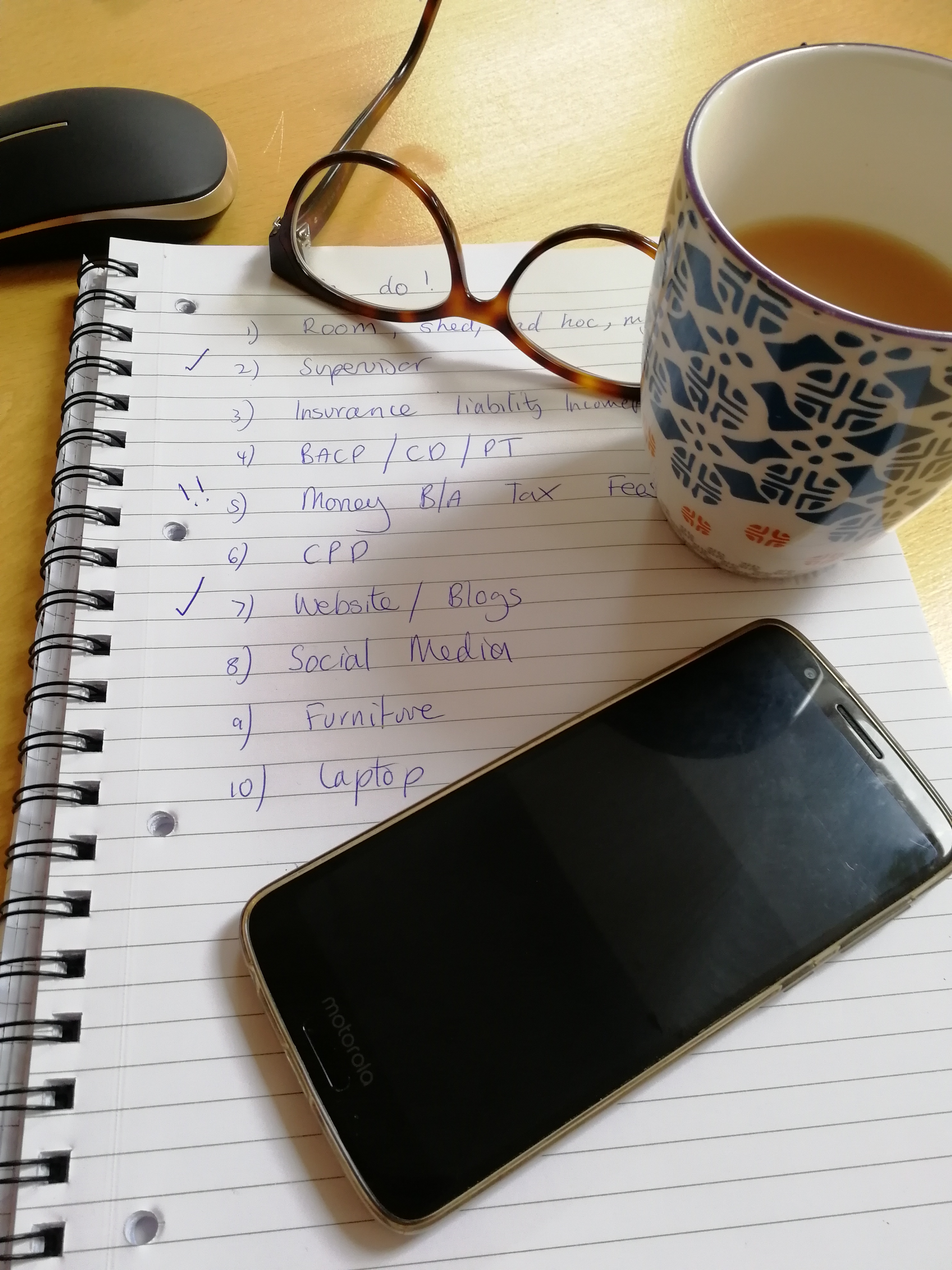Desk with glasses, tea, phone and notebook